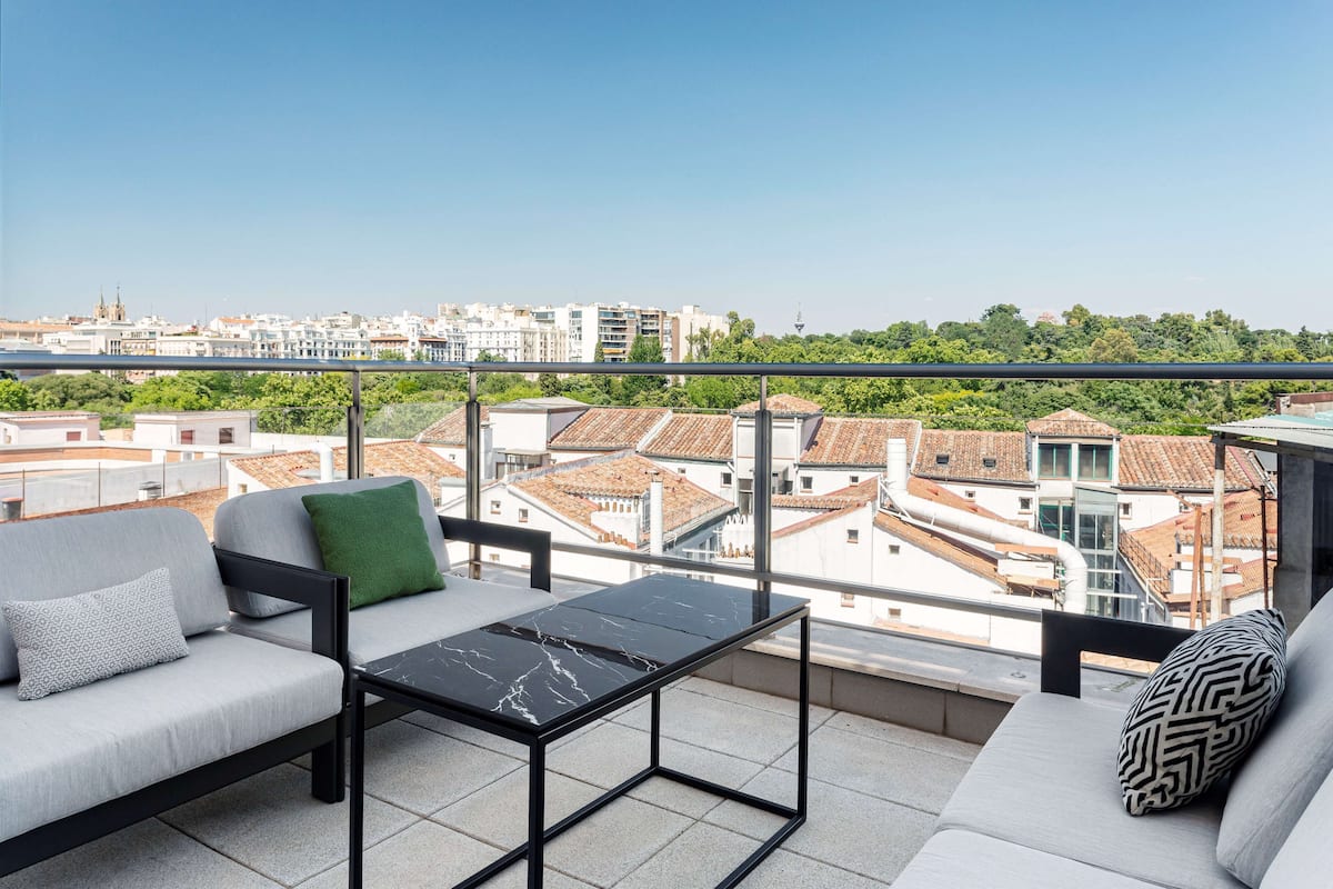 A balcony with a sofa, a small table, and a view of the cityscape.