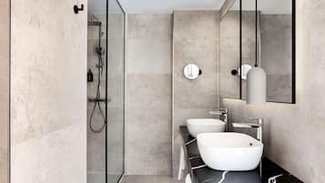 A modern bathroom with two sinks, a shower, and a large mirror.