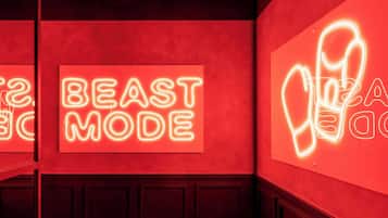 A neon sign with the words "BEAST MODE" on a red wall.