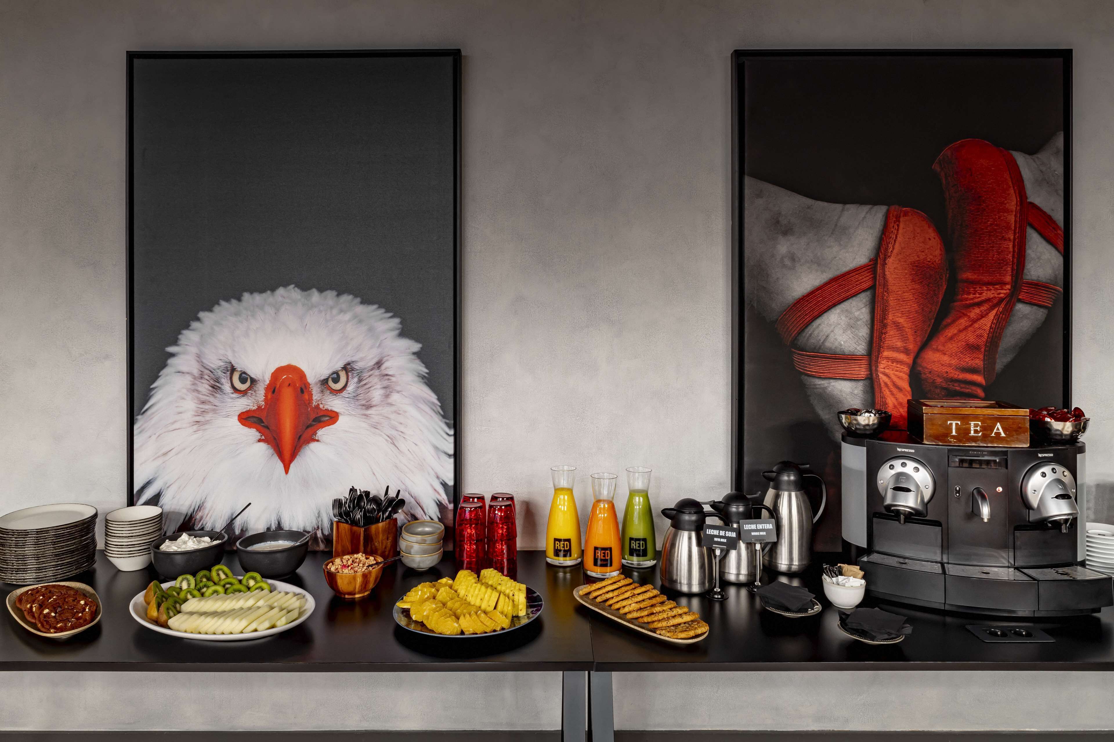 A breakfast setup with a coffee machine, various beverages, and a plate of food.