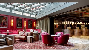 Een ruime lobby met een hoge plafond, rode bekleding en een kamerbreed tapijt met patroon.