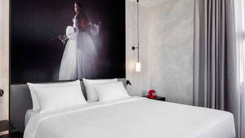 Ein Hotelzimmer mit einem großen Bett, einem Kopfteil, einem Nachttisch und einer Wandlampe.