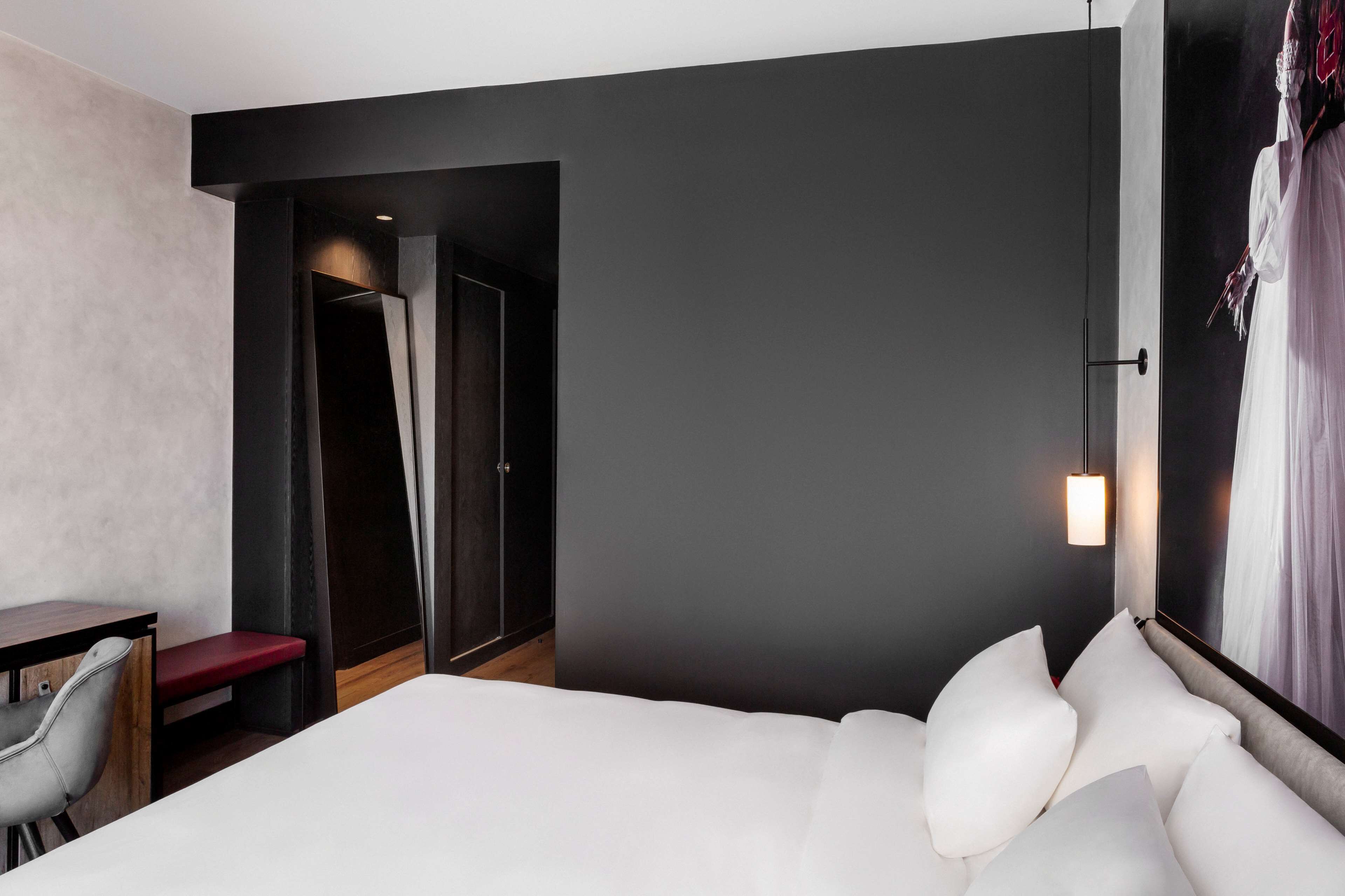 A modern hotel room with a large bed, a desk, and a chair.