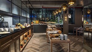 A modern restaurant with a long counter, wooden flooring, and pendant lighting.