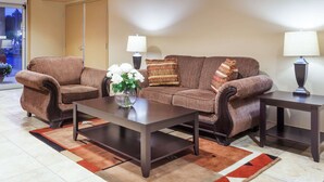 A living room with a brown sofa set, two dark wooden coffee tables, and a vase with white flowers. - Super 8 by Wyndham Abbotsford BC (Abbotsford)