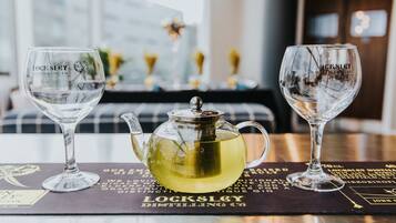 Two clear glasses and a teapot on a table with a placemat displaying text.