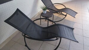 A corner seating area with two black mesh lounge chairs and a small potted plant. - Novotel Sheffield Centre (Sheffield)