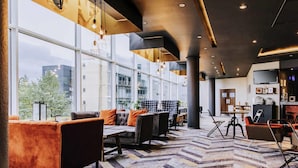 A modern lobby with seating areas, large windows, and a patterned carpet. - Novotel Sheffield Centre (Sheffield)