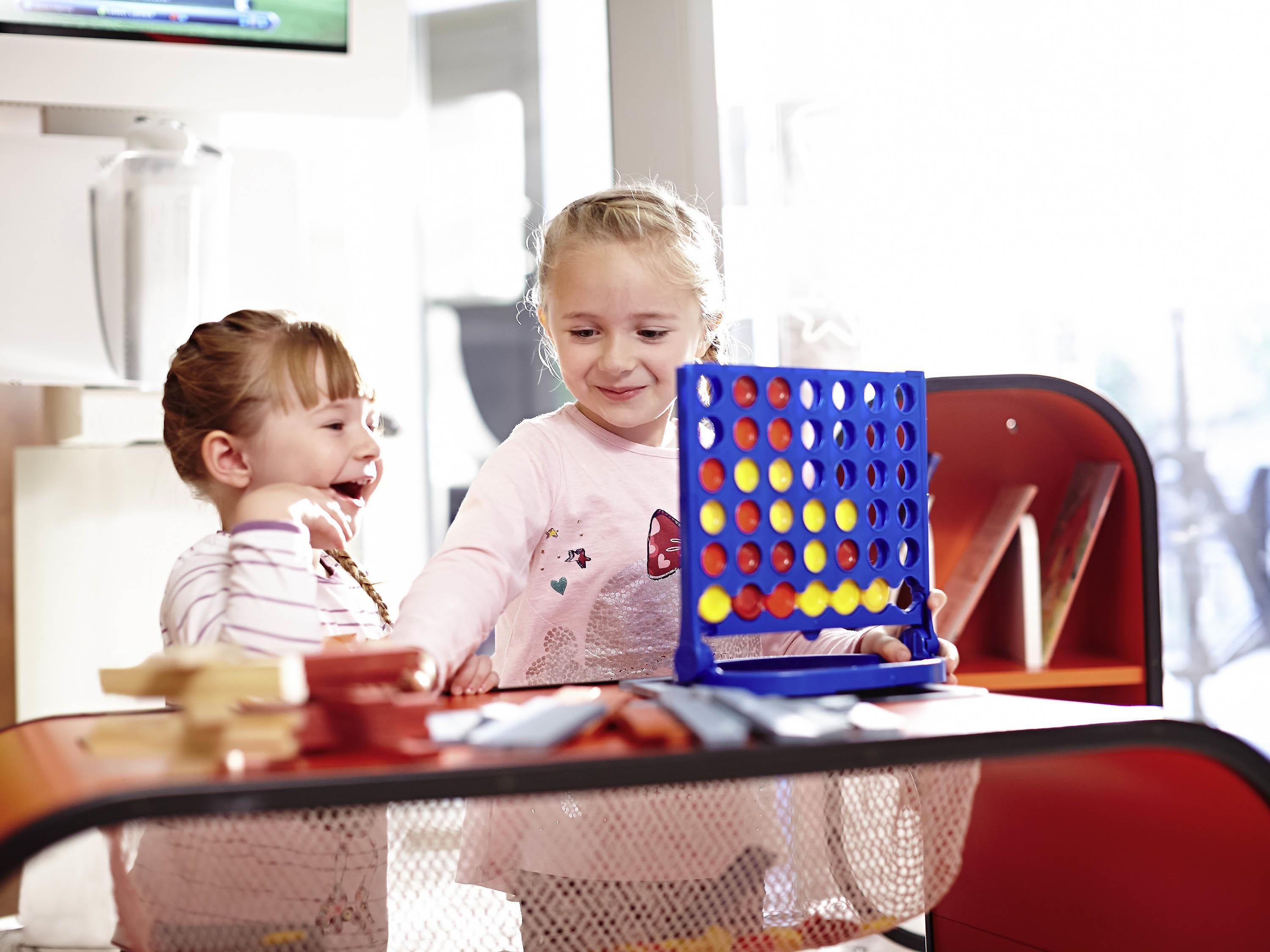Two children playing with a game on a table.