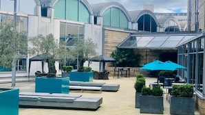 An outdoor patio area with seating, planters, and umbrellas. - Novotel Sheffield Centre (Sheffield)