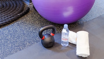 Um kettlebell, uma garrafa de água e uma toalha sobre um tapete texturizado.