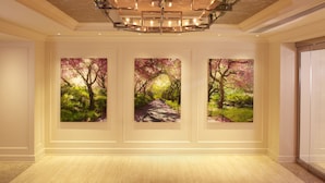 A hallway with three framed paintings of a pink pathway through a garden, a modern chandelier, and a white door. - Park Central Hotel New York (New York)