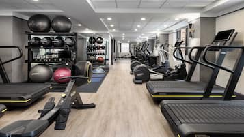 Un gimnasio moderno con cintas de correr, elípticas y varias pelotas de ejercicio.