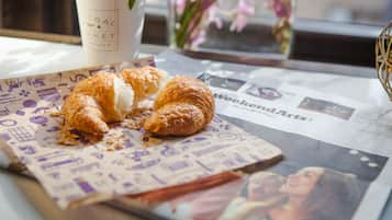 A table with a newspaper, a coffee cup, and a croissant.