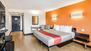 A hotel room with a bed, a desk, a chair, and a small table.