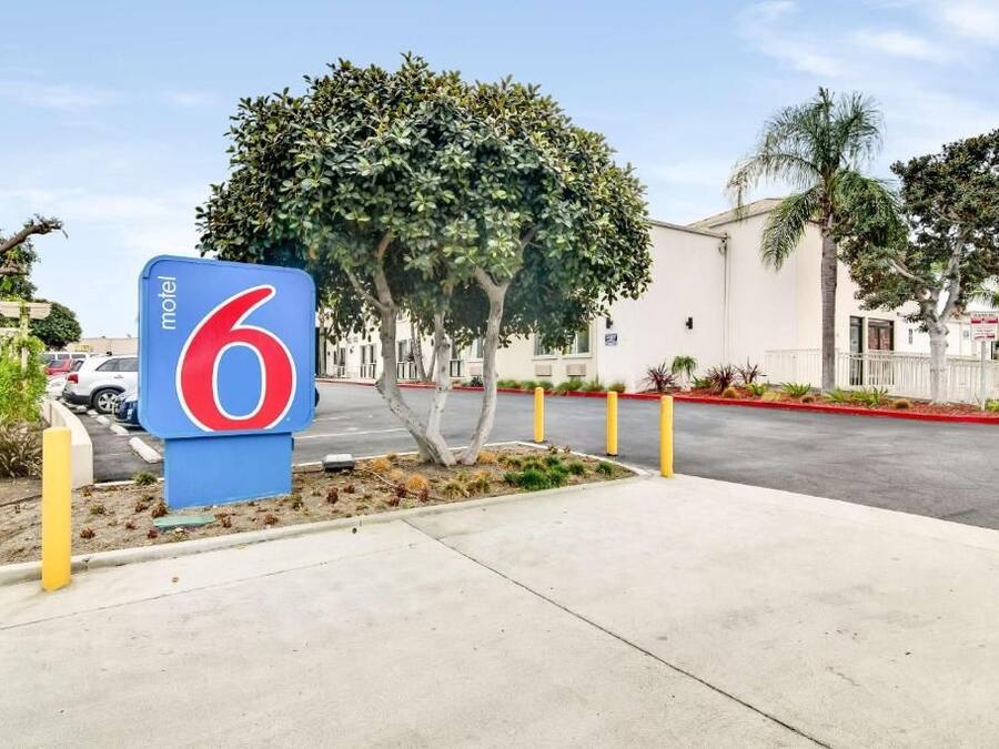 A motel sign with the number 6, a parking lot, and a building with a white facade.