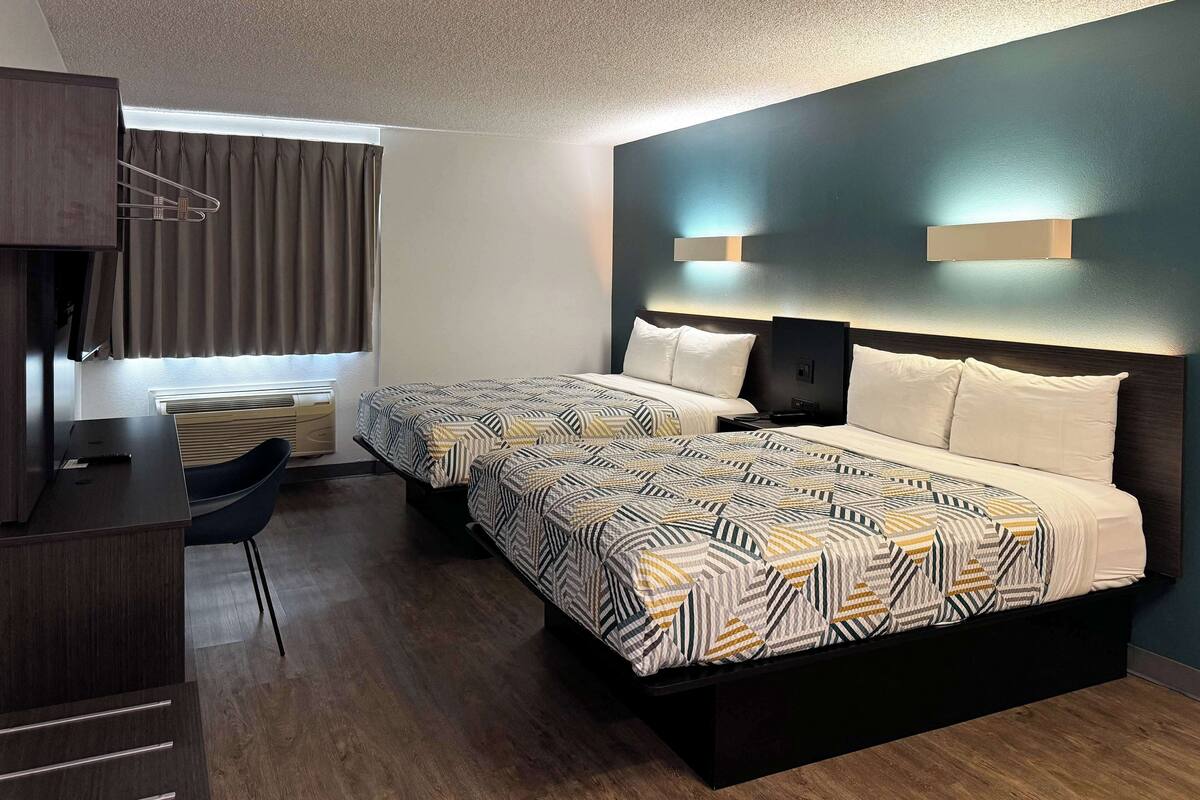 A modern hotel room with a large bed, a desk, and a chair.
