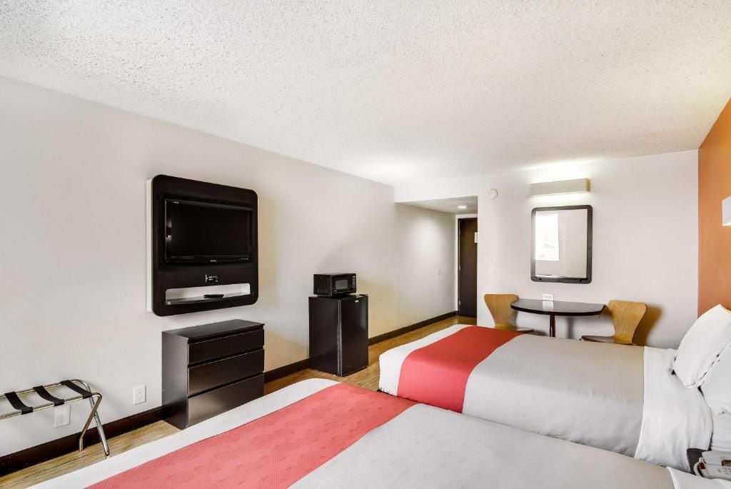 A hotel room with a bed, a TV, a desk, a chair, and a small table.