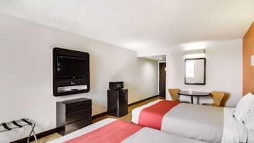 Una habitación de hotel con una cama, televisión, escritorio, silla y una pequeña mesa.