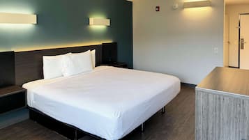 Una habitación de hotel con cama, mesitas de noche, escritorio y armario.