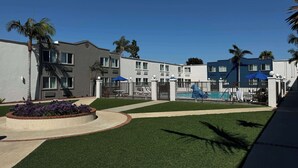 A residential building with a swimming pool, palm trees, and a well-maintained lawn. - Motel 6 Carson, CA (Carson)