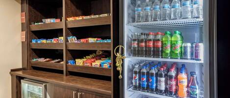 A minibar with snacks and a refrigerator stocked with various beverages.