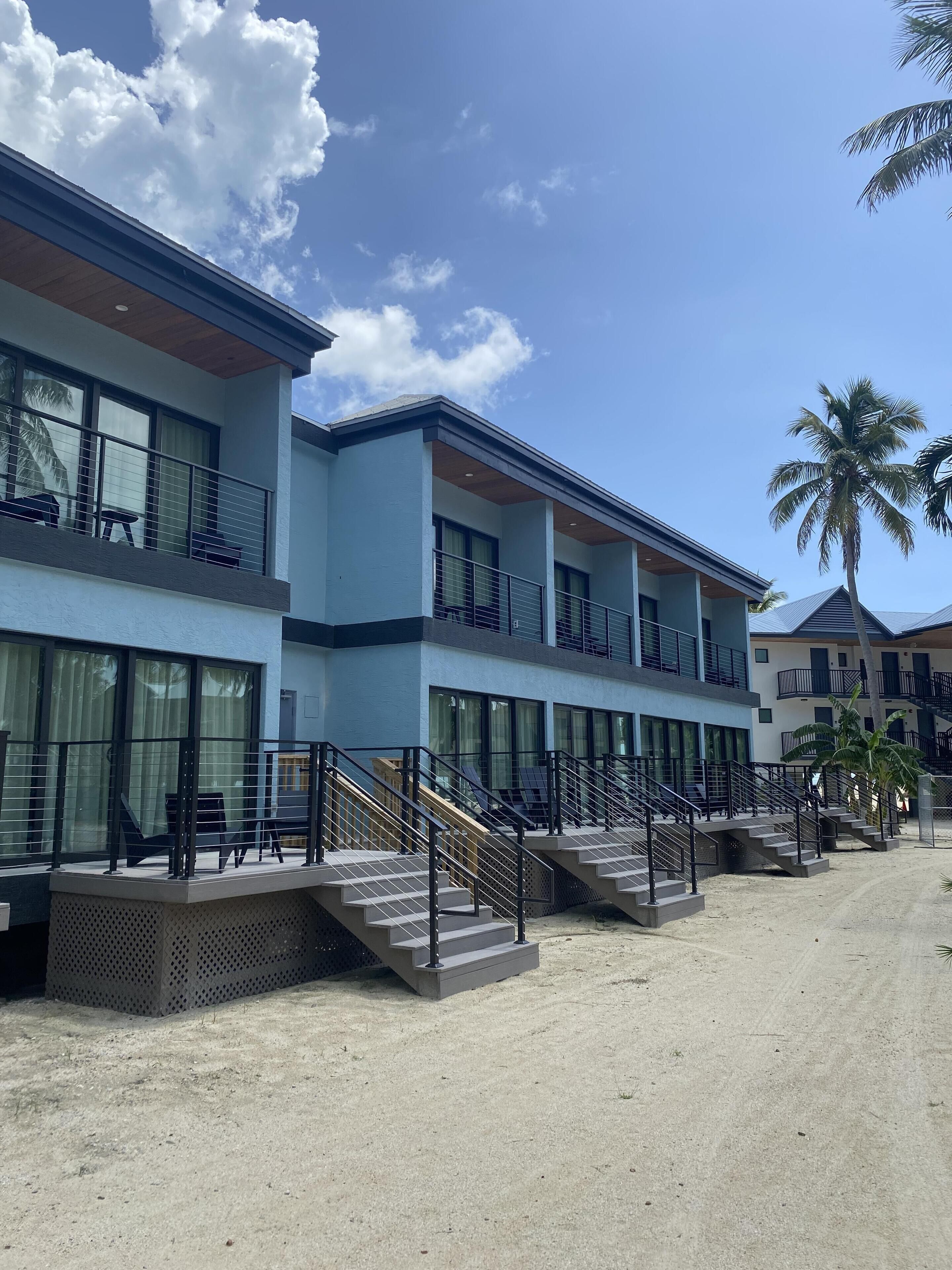 Un hôtel moderne à plusieurs étages, doté de grandes fenêtres et d’un espace extérieur couvert avec des escaliers.