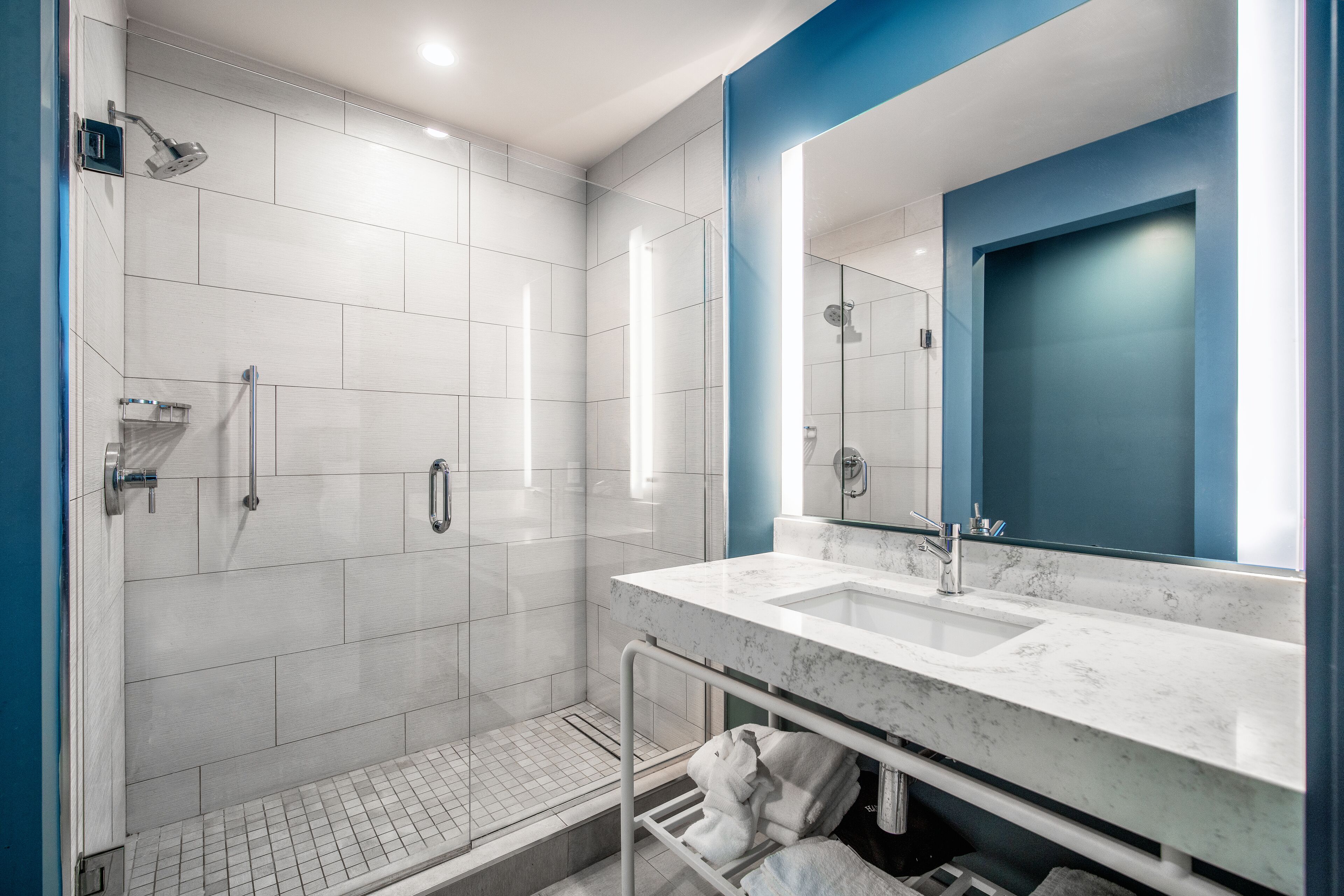 A modern bathroom with a glass-enclosed shower, two sinks, and a large mirror.
