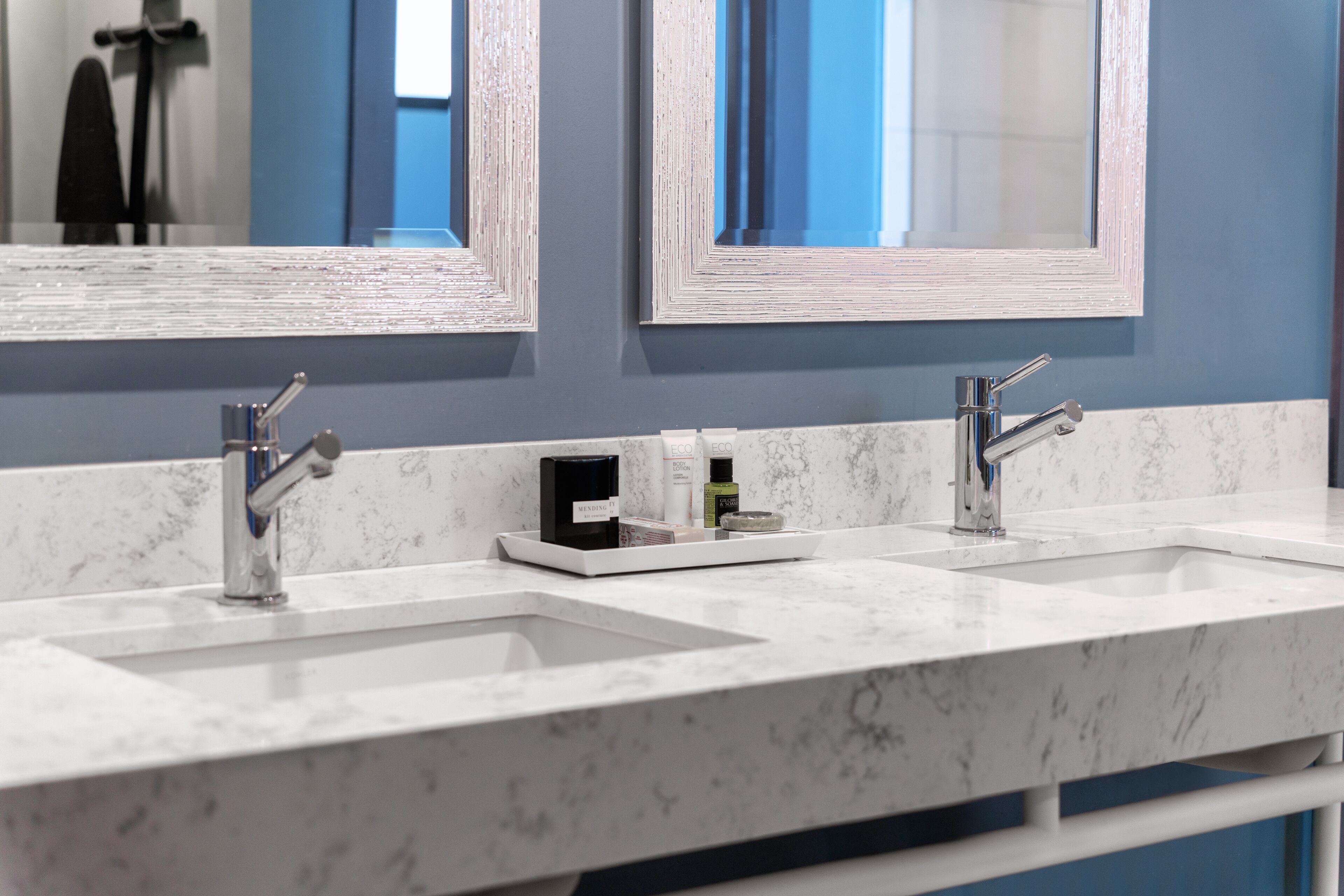 A bathroom with two sinks, a mirror, and a marble countertop.