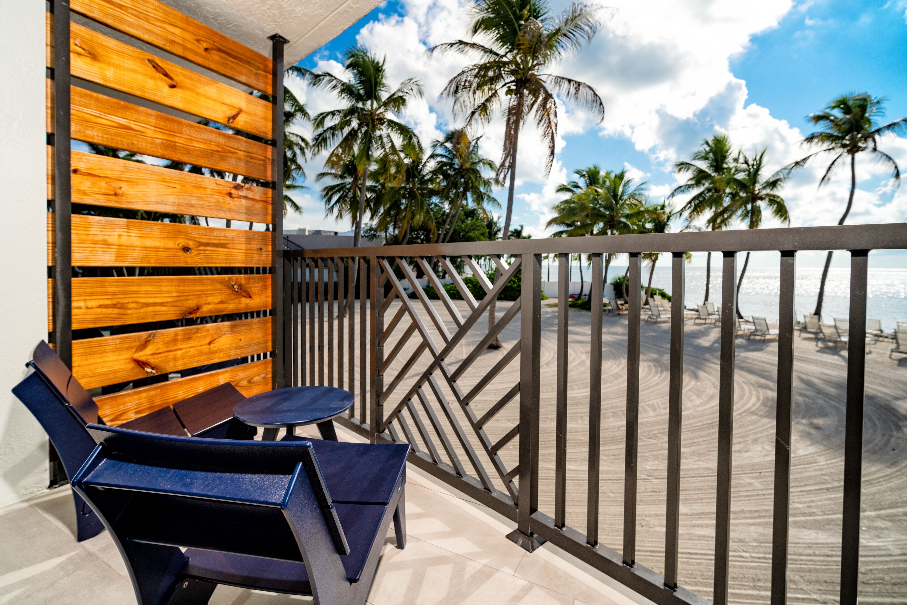 A balcony with a wooden wall, a table, and chairs.