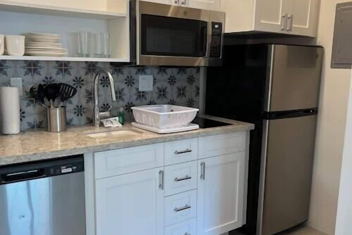 A modern kitchen with white cabinets, stainless steel appliances, and a tiled backsplash.