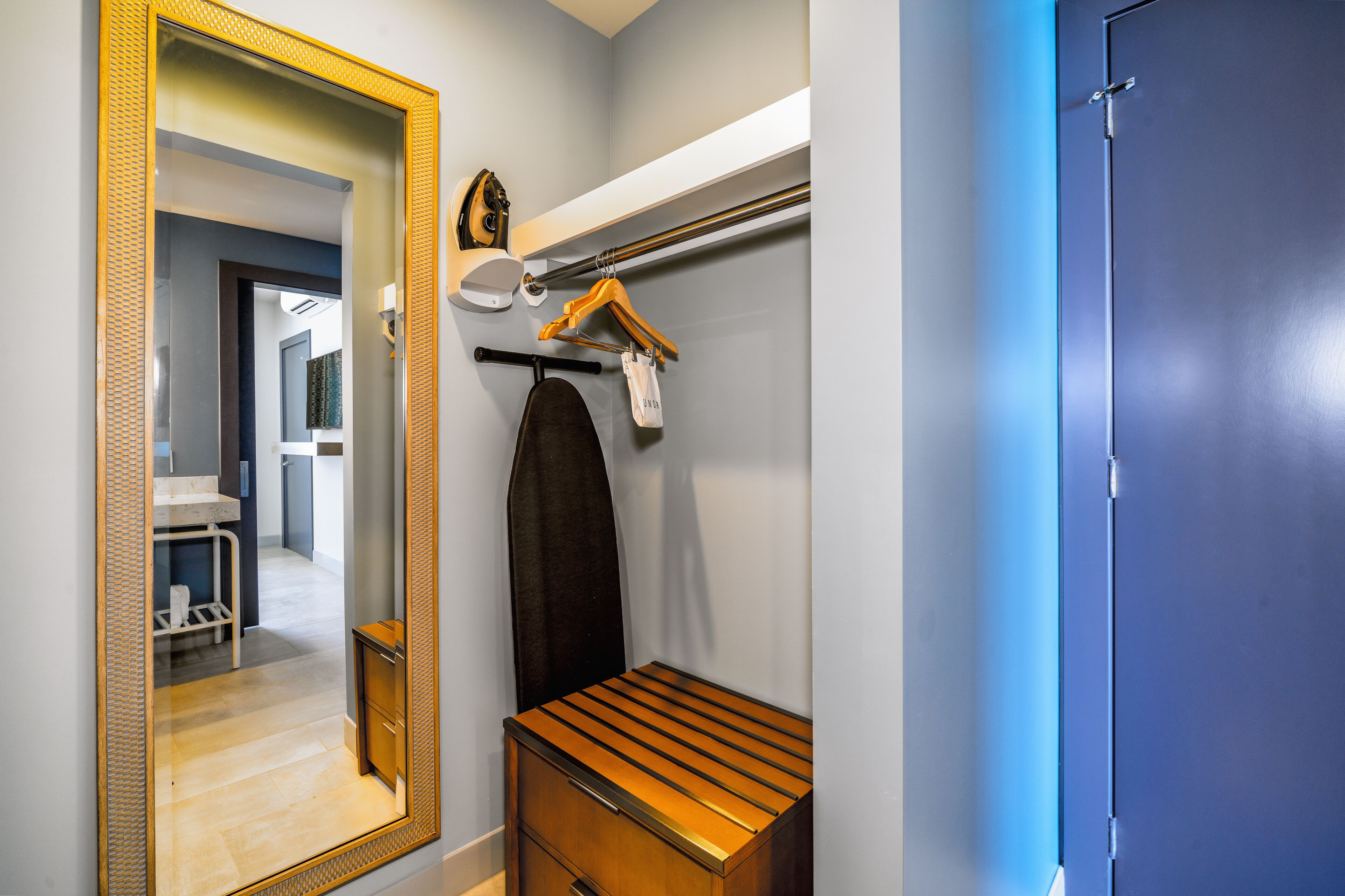 A bathroom with a mirror, towel rack, and a wooden bench.