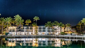 A waterfront hotel with multiple floors, palm trees, and a calm reflective pool. - Chesapeake Beach Resort (Islamorada)
