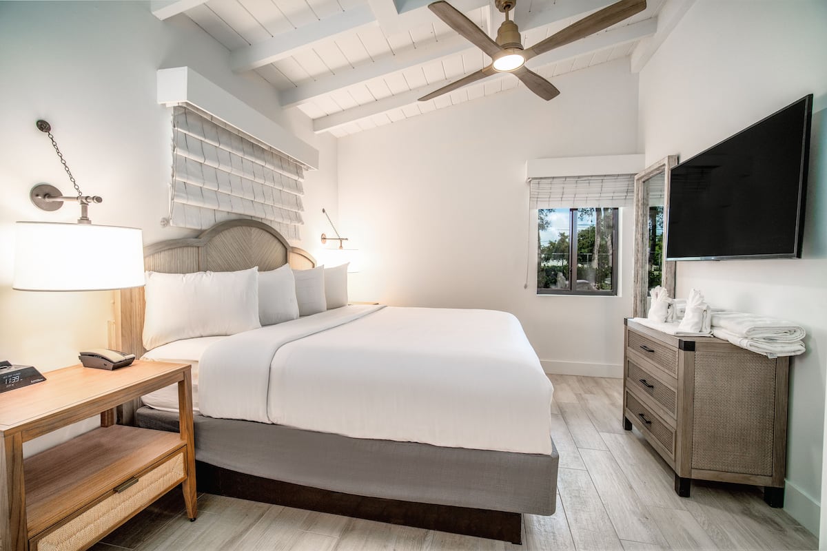 A bedroom with a bed, bedside table, lamp, and a dresser with a mirror.