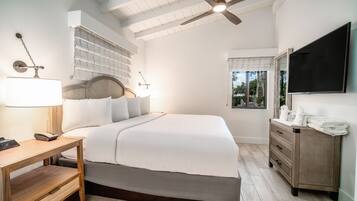 A bedroom with a bed, bedside table, lamp, and a dresser with a mirror.