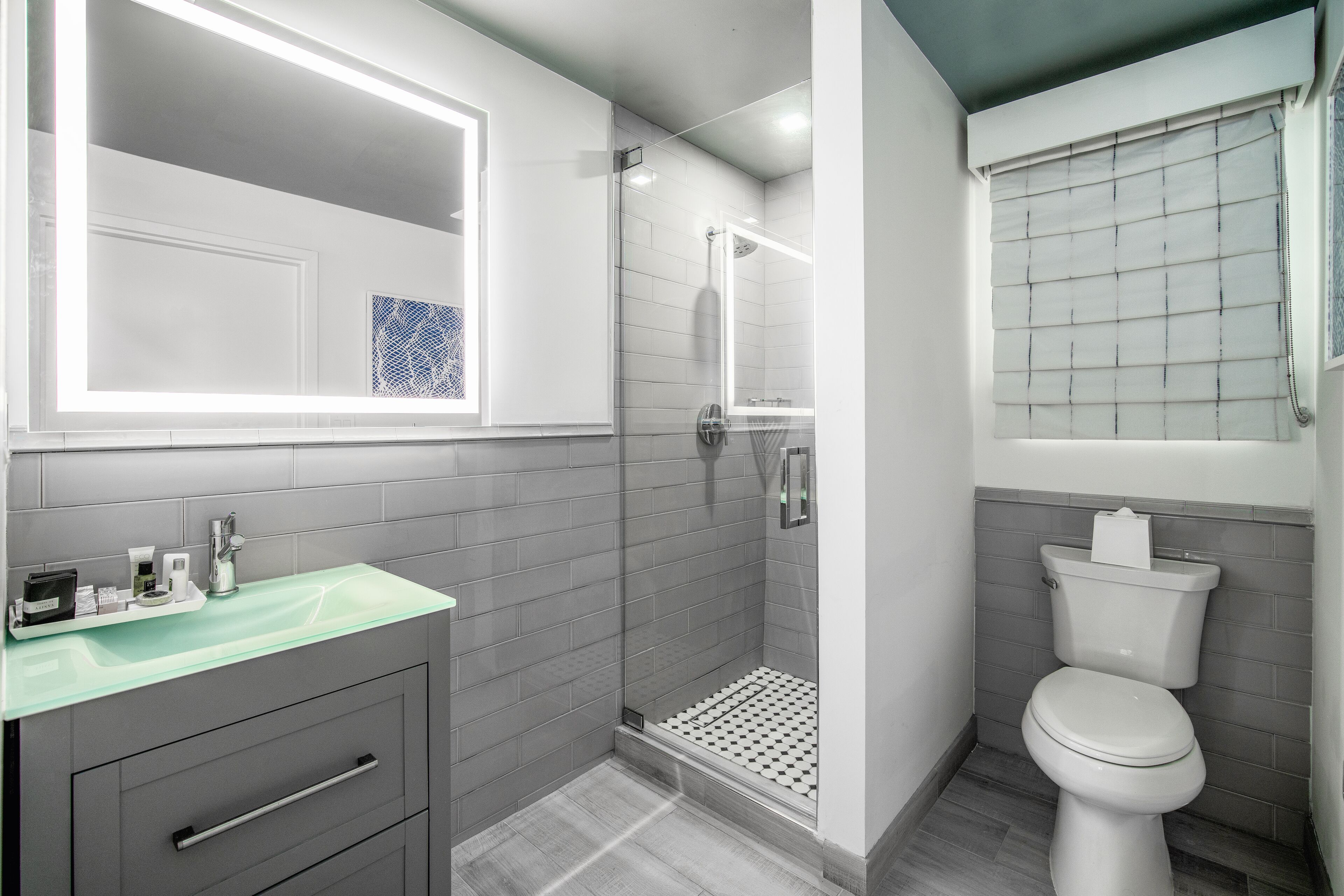 A modern bathroom with a glass shower enclosure, a white toilet, and a vanity with a glass countertop.
