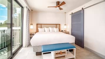 Une chambre moderne avec un grand lit, un ventilateur de plafond, des lampes de chevet, un banc et une vue sur l’extérieur grâce à une porte coulissante.