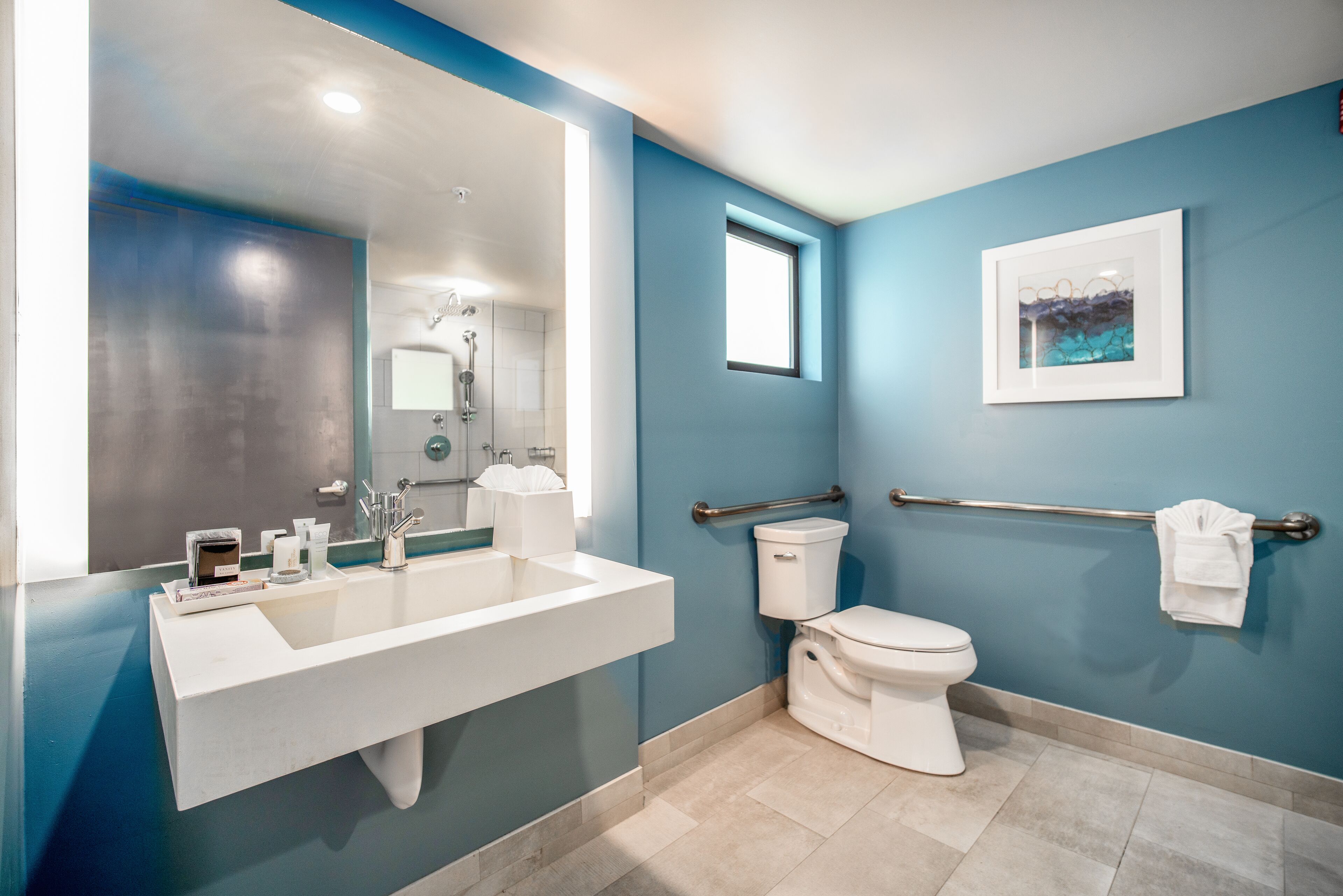 A modern bathroom with a large sink, toilet, and a window.