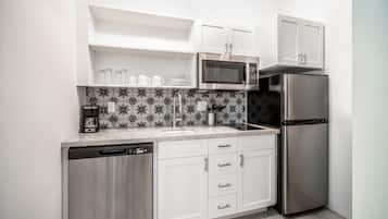 A modern kitchen with white cabinets, a stainless steel refrigerator, a microwave, and a dishwasher.