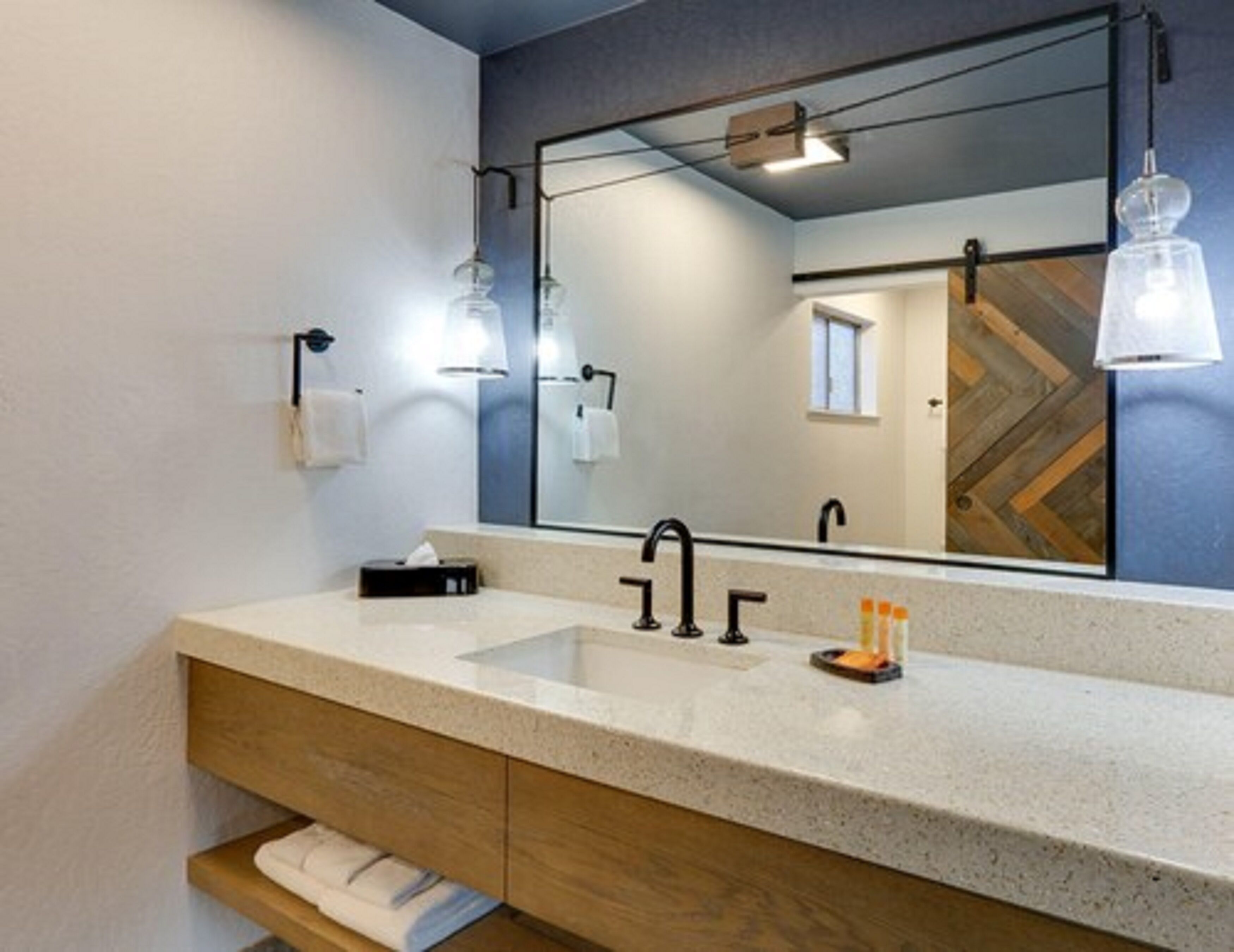 A modern bathroom with a large mirror, a sink, and a wooden vanity.