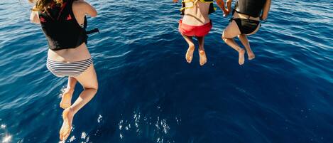 Three people jumping into the water from a boat.