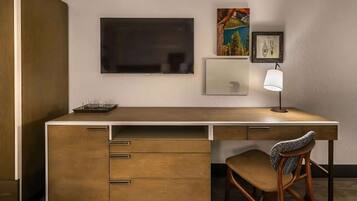 A modern desk with a flat-screen TV, a lamp, and a framed picture on the wall.