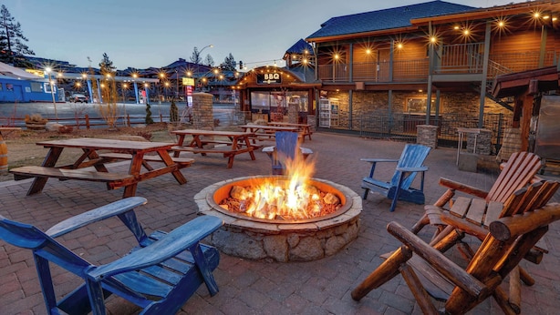 An outdoor seating area with a fire pit, picnic tables, and lounge chairs. - Hotel Becket, BW Signature Collection (South Lake Tahoe)