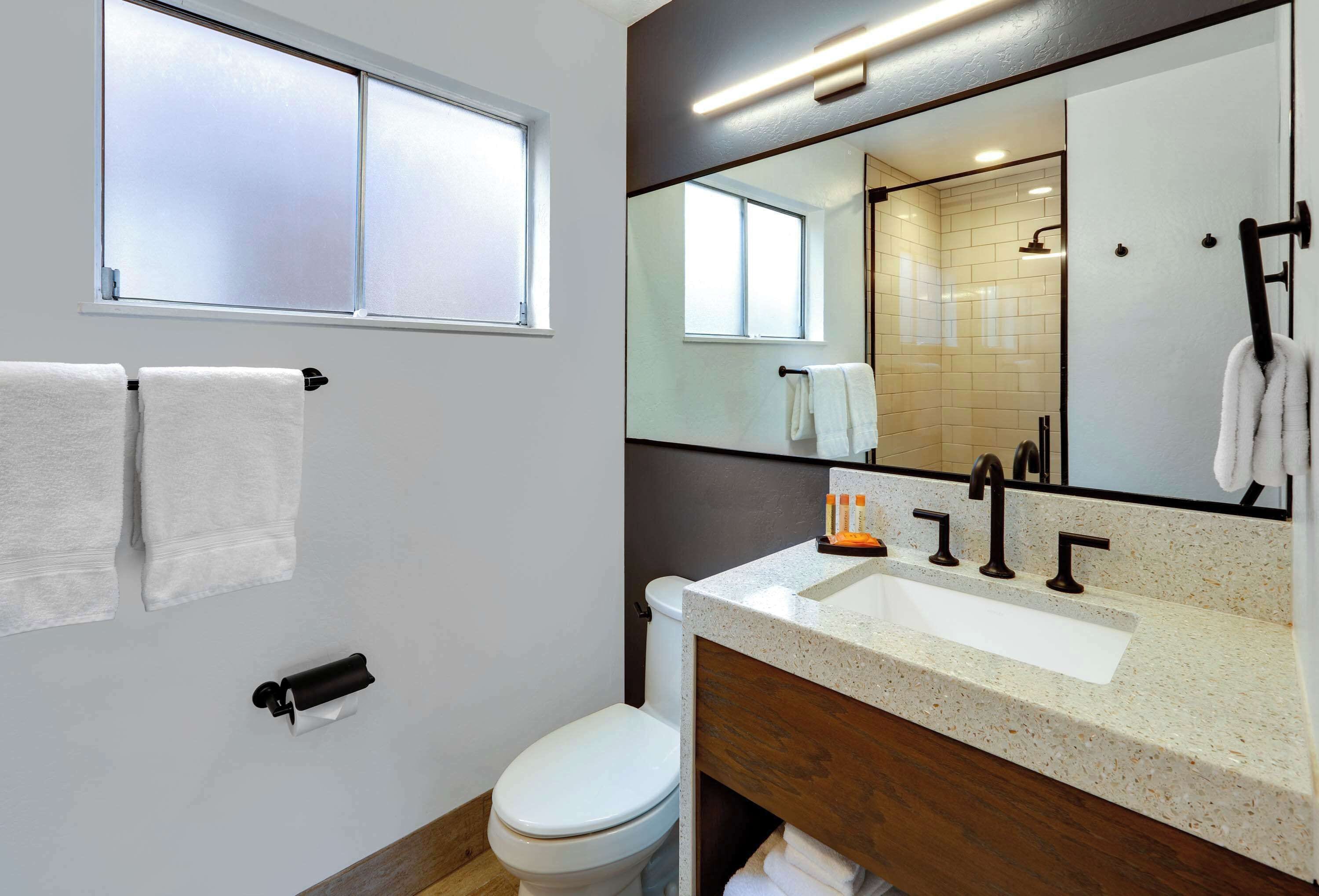Un baño moderno con inodoro, lavamanos y espejo.