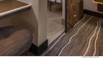 A modern bathroom with a wooden herringbone wall, a sliding barn door, a towel rack, and a small shelf.