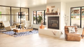 A spacious living room with a fireplace, comfortable seating, and large windows offering a view of the outside. - Hotel Becket, BW Signature Collection (South Lake Tahoe)