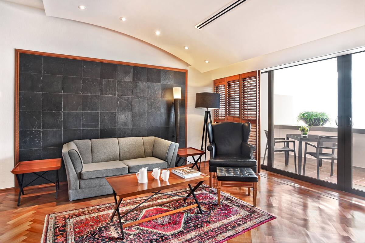Una sala de estar moderna con un sofá, un sillón, una mesa de centro y una alfombra estampada.