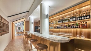 A bar area with a long counter, stools, and shelves of bottles. - Goodwood Park Hotel (Singapore)