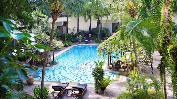 A swimming pool surrounded by palm trees and lounge chairs. - Goodwood Park Hotel (Singapore)