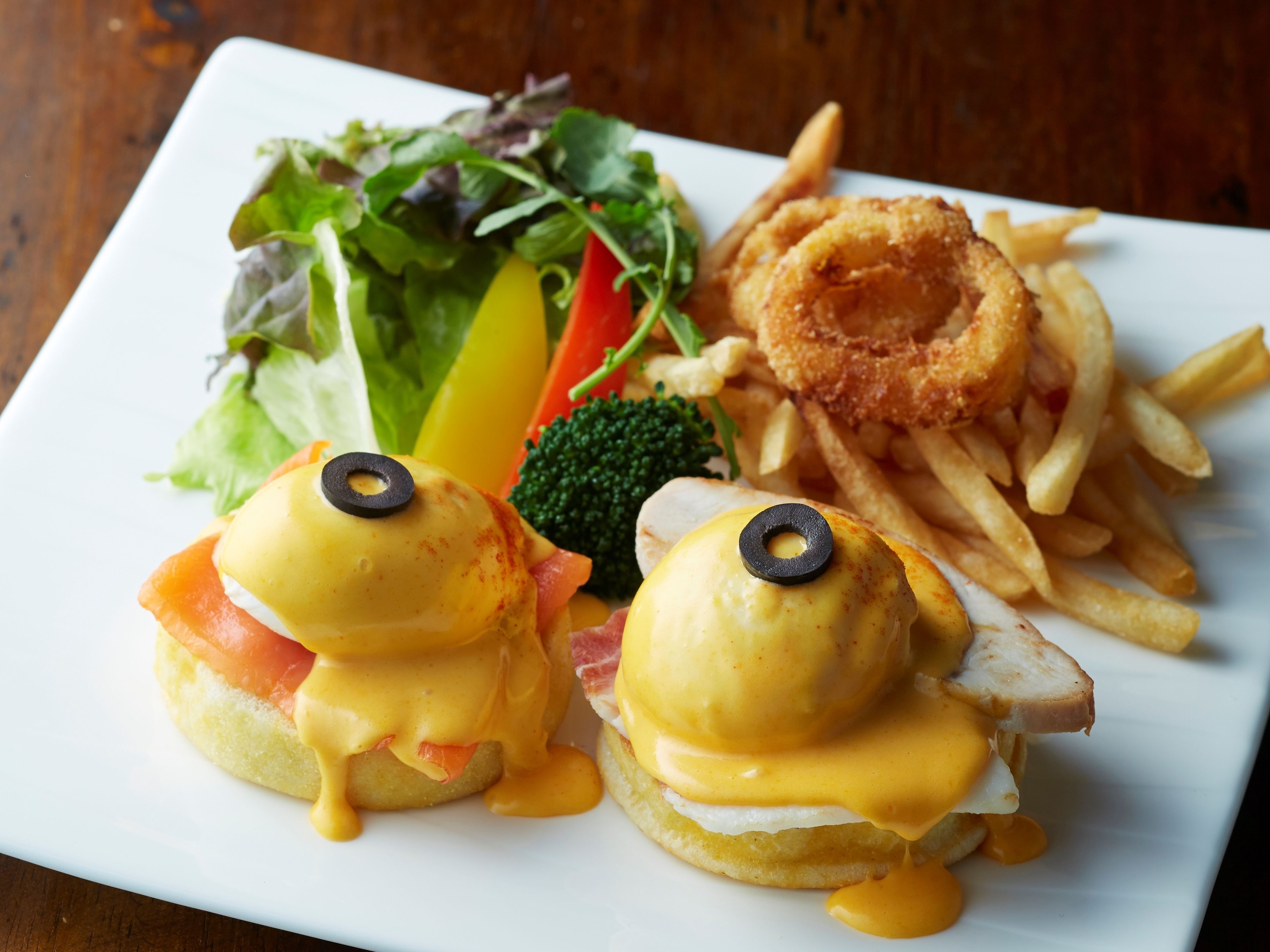 A plate with eggs benedict, fries, and a salad.